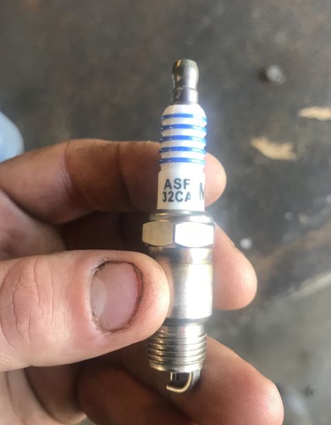 1995 Ford Bronco - A spark plug is held by a hand, showing its part number and design.