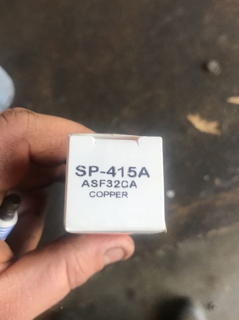 1995 Ford Bronco - A hand holds a box labeled SP-415A, ASF32CA, COPPER, with a spark plug visible to the left.