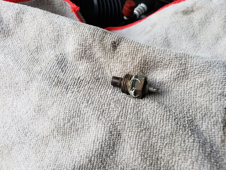 Engine sensor resting on a gray towel. Some engine parts are visible in the background