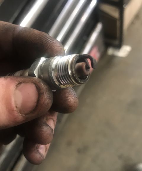 1995 Ford Bronco - A dirty hand holds a used spark plug, showing wear on the electrode.