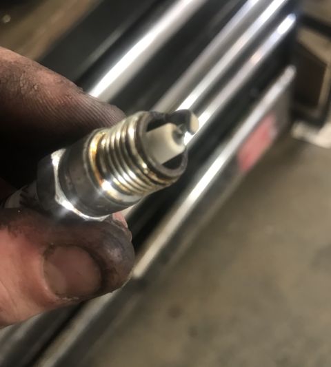 1995 Ford Bronco - A dirty hand holds a used spark plug, with the Supermotors.net logo in the background.