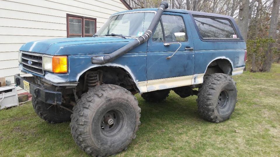 Blue Ford Bronco with large off-road tires and snorkel, front 3/4 view