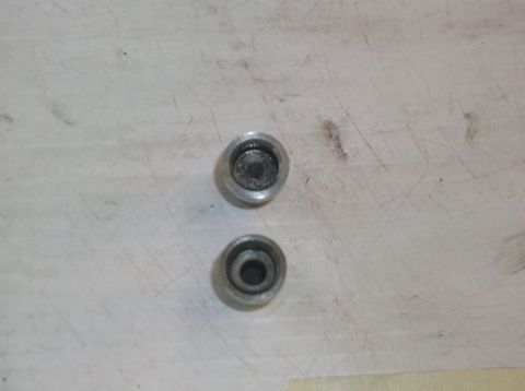 1979 Ford Ranchero - Two metal caps with recessed centers are shown on a light-colored surface.
