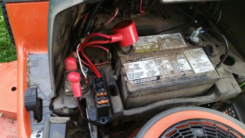 2007 Subaru Impreza - Close-up view of a tractor's battery, wiring, and fuse box, showing red terminal covers and fuses.