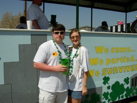 1995 Ford Bronco - Couple poses in front of a wall decorated with shamrocks and text about partying.