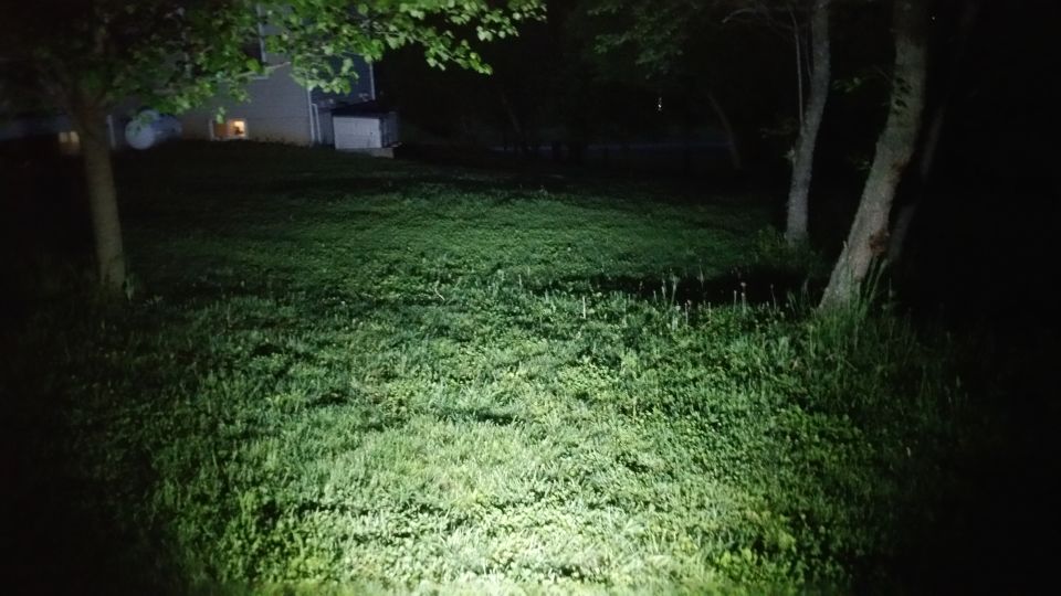 Lawn illuminated by bright light at night, Supermotors.net logo visible