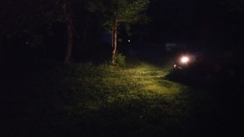 2007 Subaru Impreza - A vehicle's headlights are on in a dark, grassy outdoor setting.