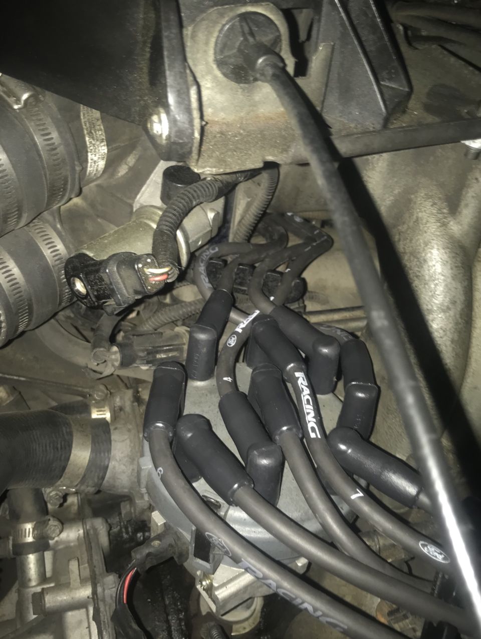 Engine bay with spark plug wires, some labeled "RACING" and "FORD"