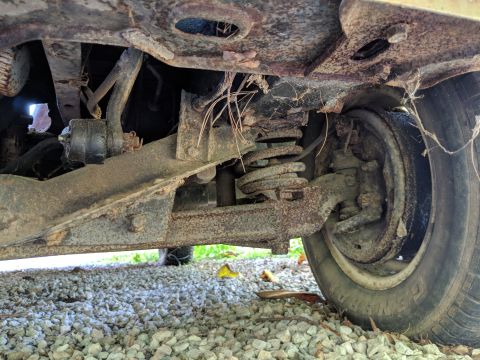 1971 Ford Ranchero - Close-up view of the rusty undercarriage and suspension components of a vehicle.