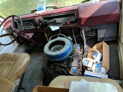 1971 Ford Ranchero - The interior of a vehicle reveals an exposed engine, dashboard, and worn seats, with oil bottles and a SuperMotors logo visible.