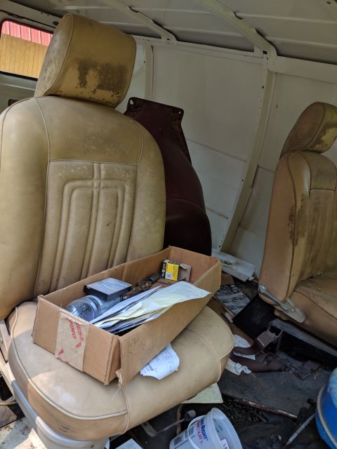 1971 Ford Ranchero - The interior of a vehicle shows worn seats and a cardboard box filled with various items, suggesting it is being used for storage or transp…