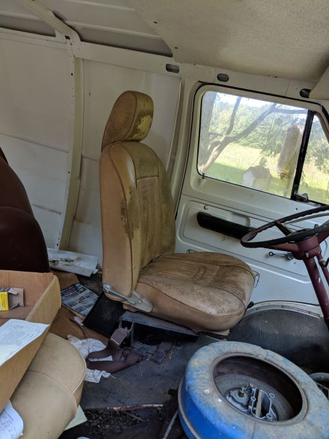 1971 Ford Ranchero - Interior view of a white van, showing a worn driver's seat, spare tire, and scattered items.