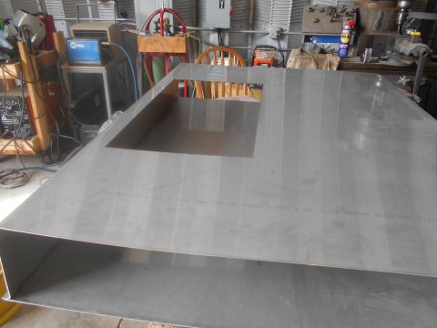 1992 Ford Bronco - A large piece of sheet metal with a cut-out is shown in a workshop setting, with various tools and equipment visible.