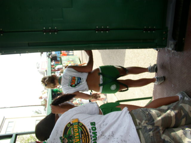 People in green shorts and t-shirts near a green portable toilet