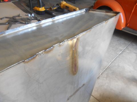 1992 Ford Bronco - A close-up view of a freshly welded metal panel, with part of an orange vehicle visible in the background.