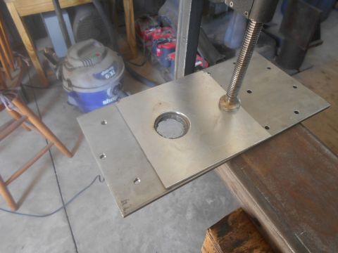 1992 Ford Bronco - A metal plate with a central hole and a screw mechanism is shown, likely a component for a larger machine or tool.