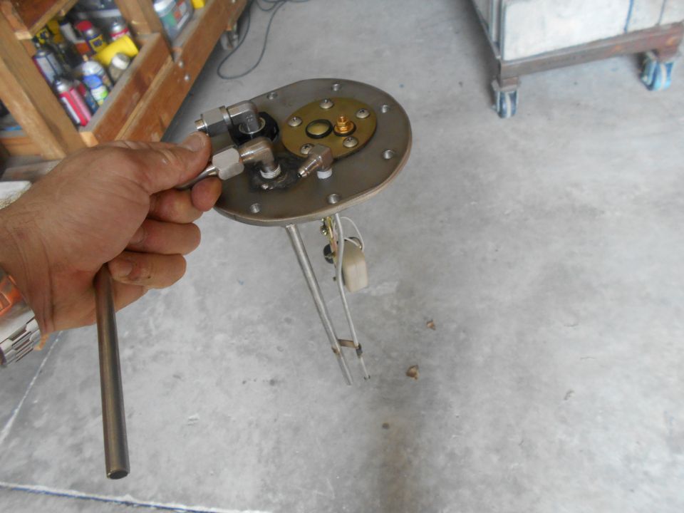 Hand holding a metal fuel sending unit with a float arm and electrical connections