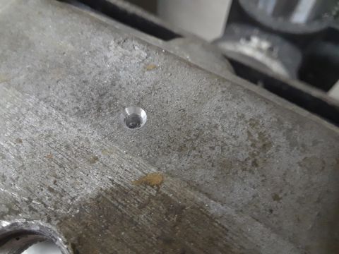 1985 Ford Bronco - A close-up view of a metal engine component, showing a newly drilled hole.