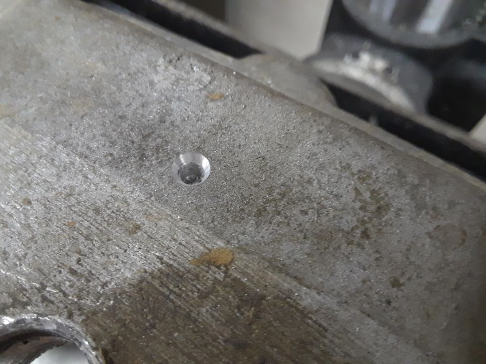Close-up of a metal engine part with a drilled hole