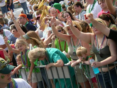 1995 Ford Bronco - People in a crowd are watching an event, many wearing green beads and some with face paint.