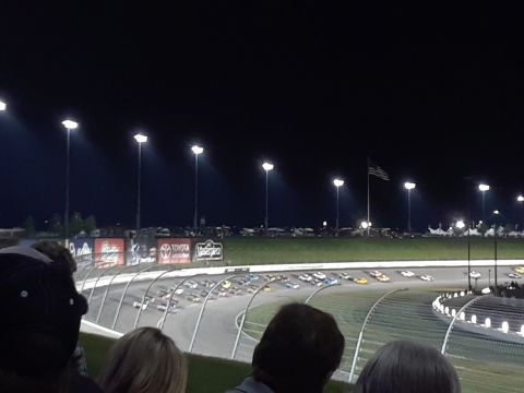 1994 Ford Bronco - A nighttime race is underway on a track, with multiple cars visible under bright stadium lights.