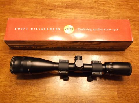 1995 Mercury Grand Marquis - Swift rifle scope and its original packaging box are displayed on a wooden surface.