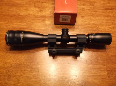 1995 Mercury Grand Marquis - A rifle scope and its box are displayed on a wooden table.