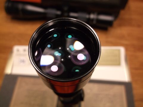 1995 Mercury Grand Marquis - Reflections are visible on the objective lens of a rifle scope, with another scope in the background.