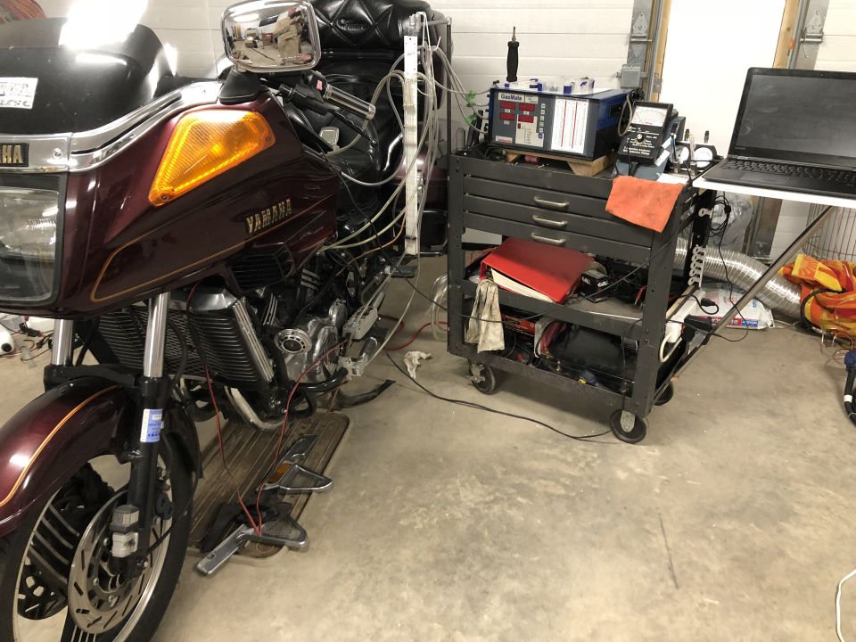 Maroon Yamaha touring motorcycle on a shop floor beside a diagnostic tool cart