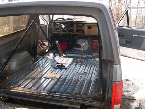 1986 Ford Bronco - The interior of an SUV has been stripped down, revealing the metal floor and dashboard components.