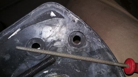 2000 Pontiac Grand Prix - A file is used on a black plastic automotive part, showing mounting holes and a bolt.