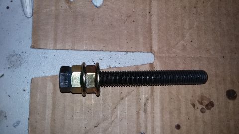 2000 Pontiac Grand Prix - A single bolt with nuts and washers is shown on a piece of cardboard.