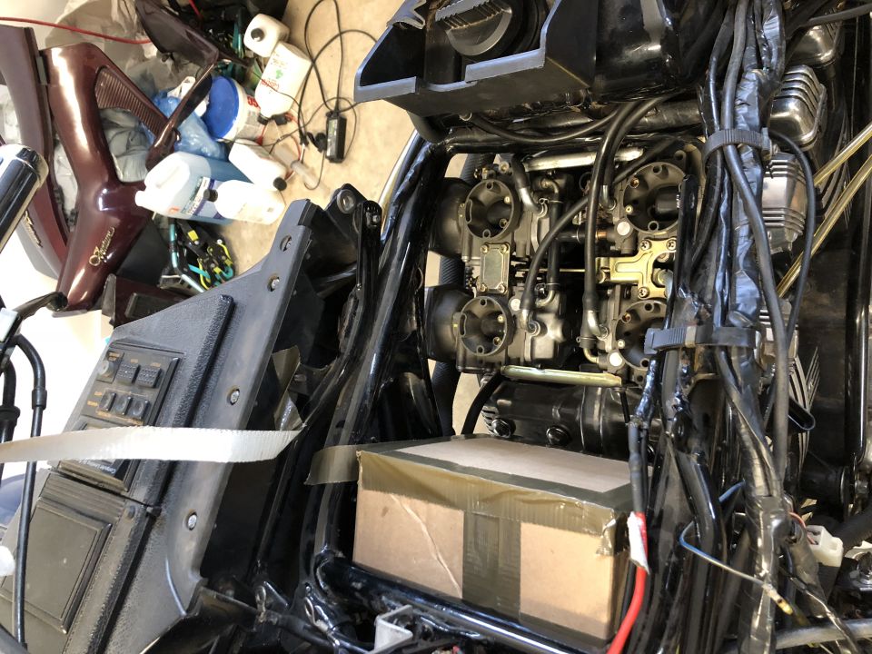 Motorcycle engine and frame stripped down for restoration in a cluttered garage