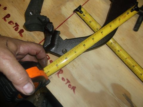 1979 Ford Ranchero - A hand uses a measuring tape to measure a brake caliper, with the word 'Rotor' visible on the wooden surface.