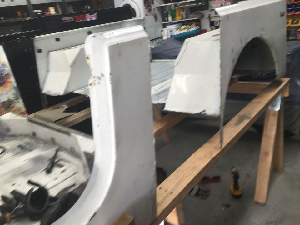 White Jeep Wrangler fender and quarter panel sections on sawhorses in a workshop