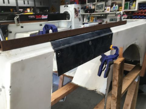 1992 Jeep Wrangler - A white vehicle body panel is undergoing repair work, secured with clamps and a metal attachment.