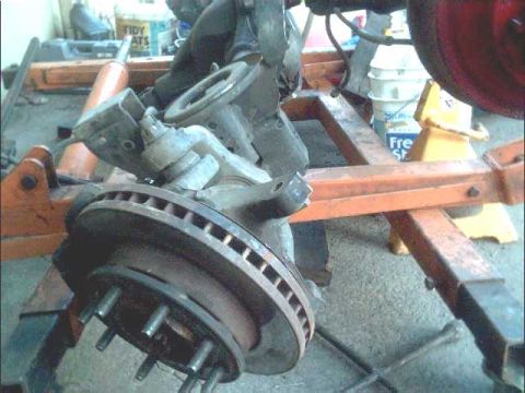 1978 Ford Bronco - Close-up view of a vehicle's front brake rotor and suspension components, likely undergoing maintenance or repair.