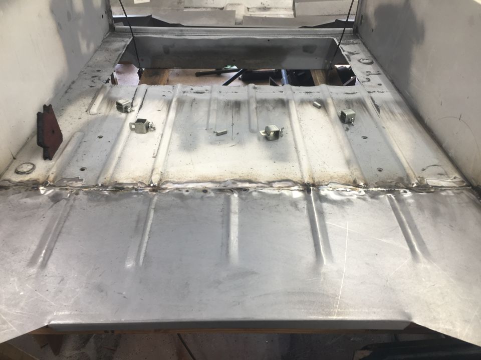 Vehicle interior floor with metal panels, visible welds, and tie-down points