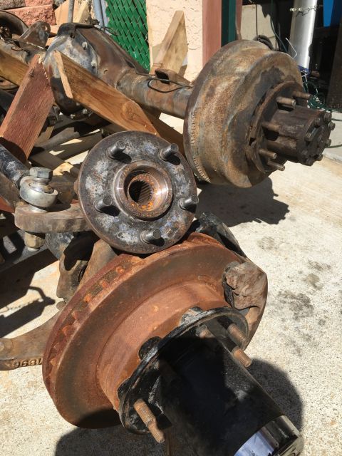 1992 Jeep Wrangler - Close-up of rusty vehicle axles and hubs, likely for a heavy-duty application.