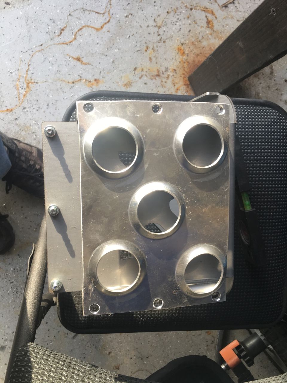 Metal plate with five circular openings, possibly for gauges or vents