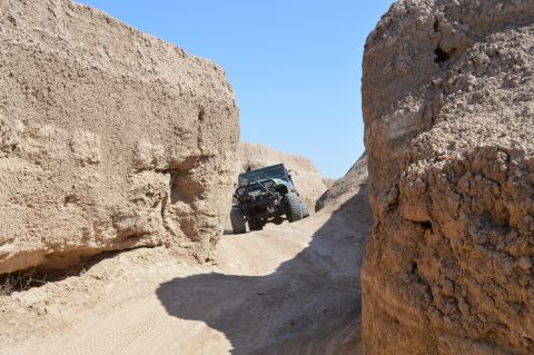 1992 Jeep Wrangler - Jeep Wrangler driving off-road through a narrow, sandy canyon under a clear blue sky.