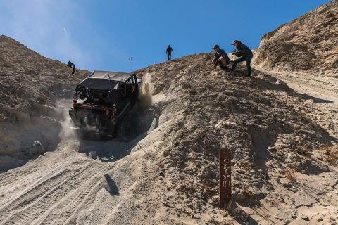 1992 Jeep Wrangler - Off-road vehicle navigates a challenging sandy descent with spectators observing the action.