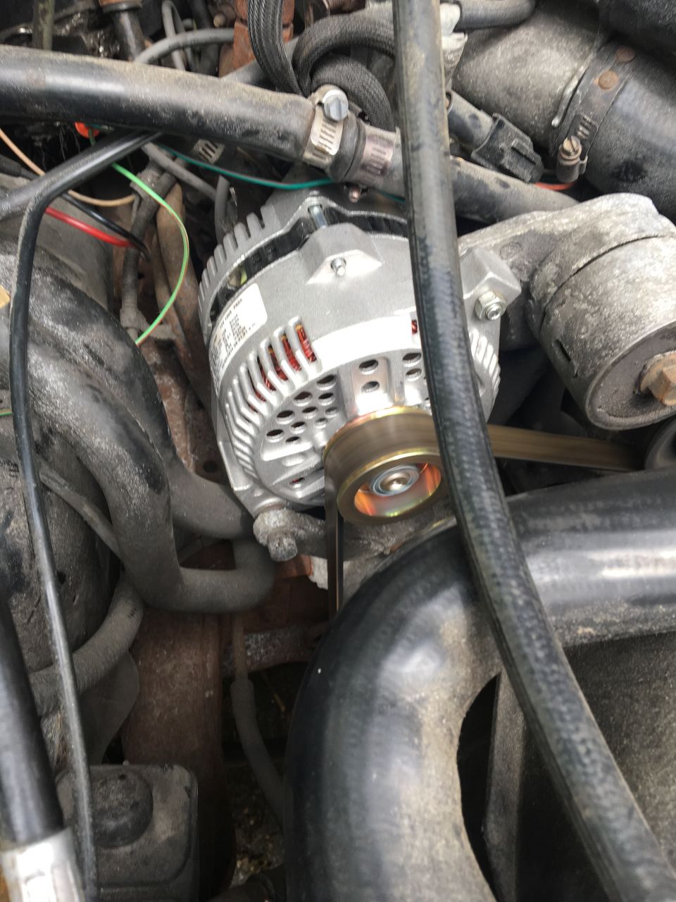 Close-up of a vehicle's alternator with hoses and wiring visible
