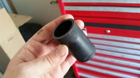 1985 Ford Bronco - A person holds a black rubber adapter in front of a red toolbox.