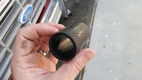 1985 Ford Bronco - Hand holding a rubber hose part with a Ford grille in the background.