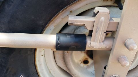 1985 Ford Bronco - A close-up view of a spare tire mount assembly, showing a socket tool attached to a metal bar.