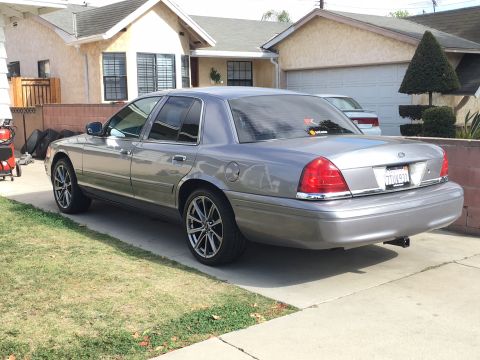 1989 Mazda MX-6 - Rear view of a gray Ford Crown Victoria with custom wheels, parked in a residential driveway.