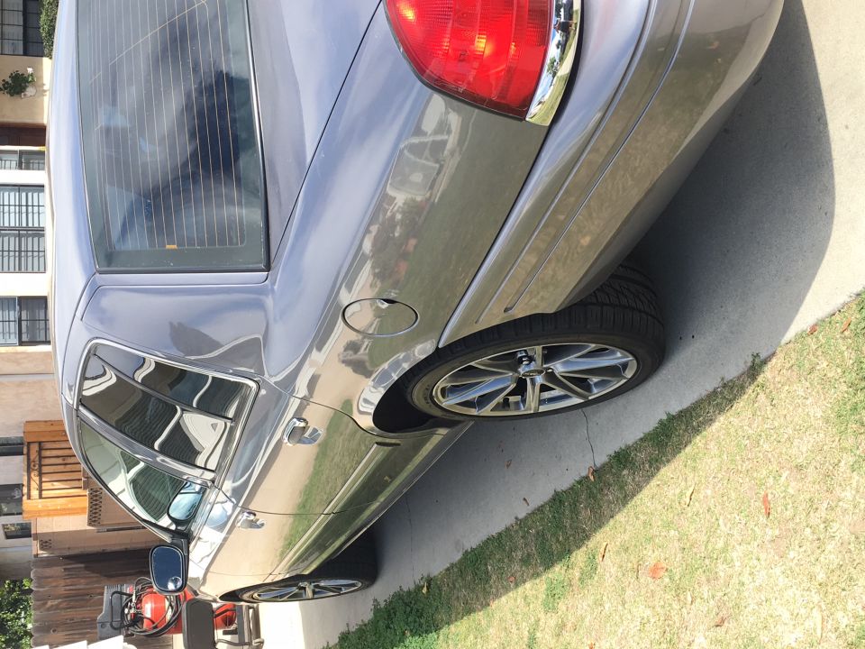 Gray sedan parked on a driveway, showing the rear passenger side wheel and taillight