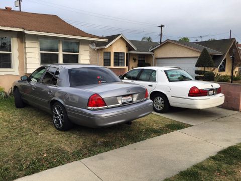 1989 Mazda MX-6 - Two sedans, one gray and one white, are parked in a residential driveway.