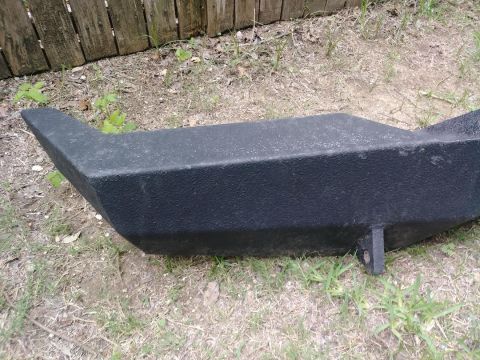 1996 Ford Bronco - A black aftermarket bumper is shown from an angled perspective, resting on grass in front of a wooden fence.